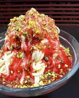 Ein Spaghettieis mit frischer Erdbeersauce, garniert mit gerösteten Pistazienstücken