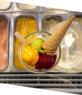 Eine bunte Schale mit gelbem, grünem und rotem Eissorbet sowie einer knusprigen Eiswaffel dazu 