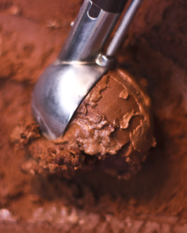 Eine Eislöffel schöpft das beliebte dunkle Schokoladeneis aus der Truhe